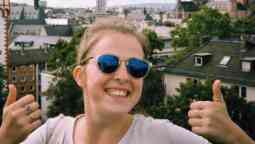 Female smiling at the camera with both thumbs up with a Germany city scape in the background