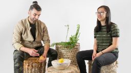 Two students sit on planters with various decor objects they made