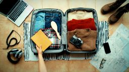 A person is packing their belongings into a travel suitcase