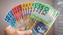 A hand holding Australian banknotes