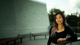 International asian student Thao. smiling towards the camera wearing a black top and hair flowing over her right shoulder.