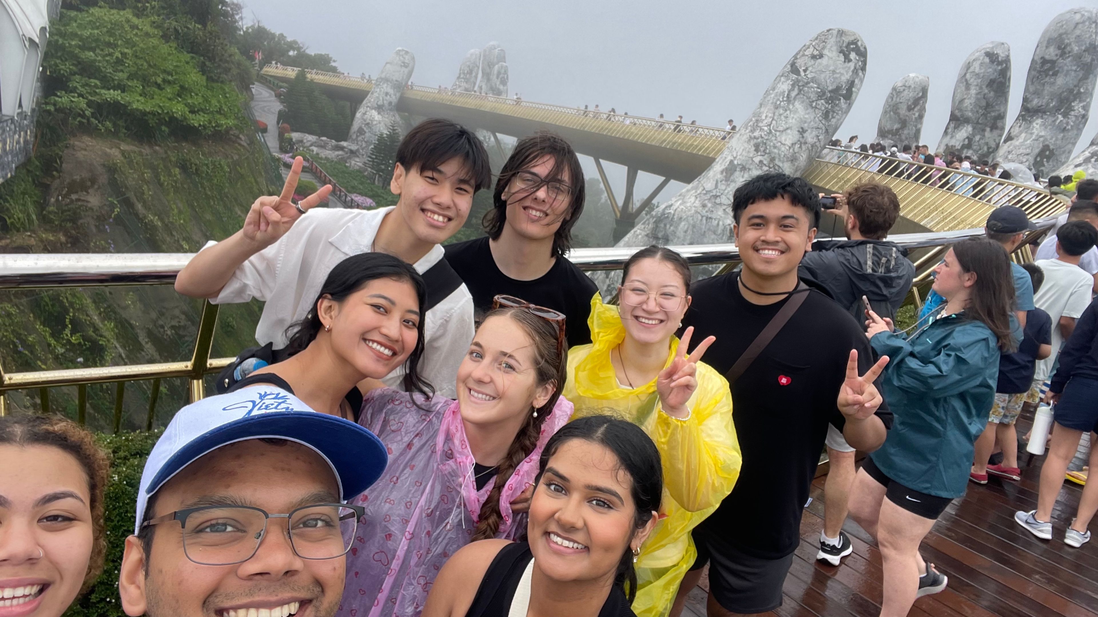 Selfie of a group of students on Golden Bridge, Vietnam, huge stone hands hold up curving bridge in the mist