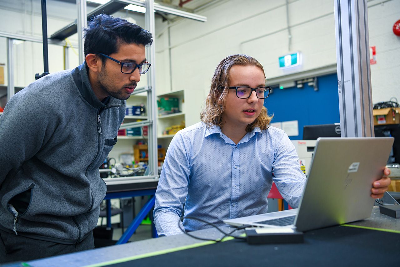 julian working with coworker student working with someone on laptop
