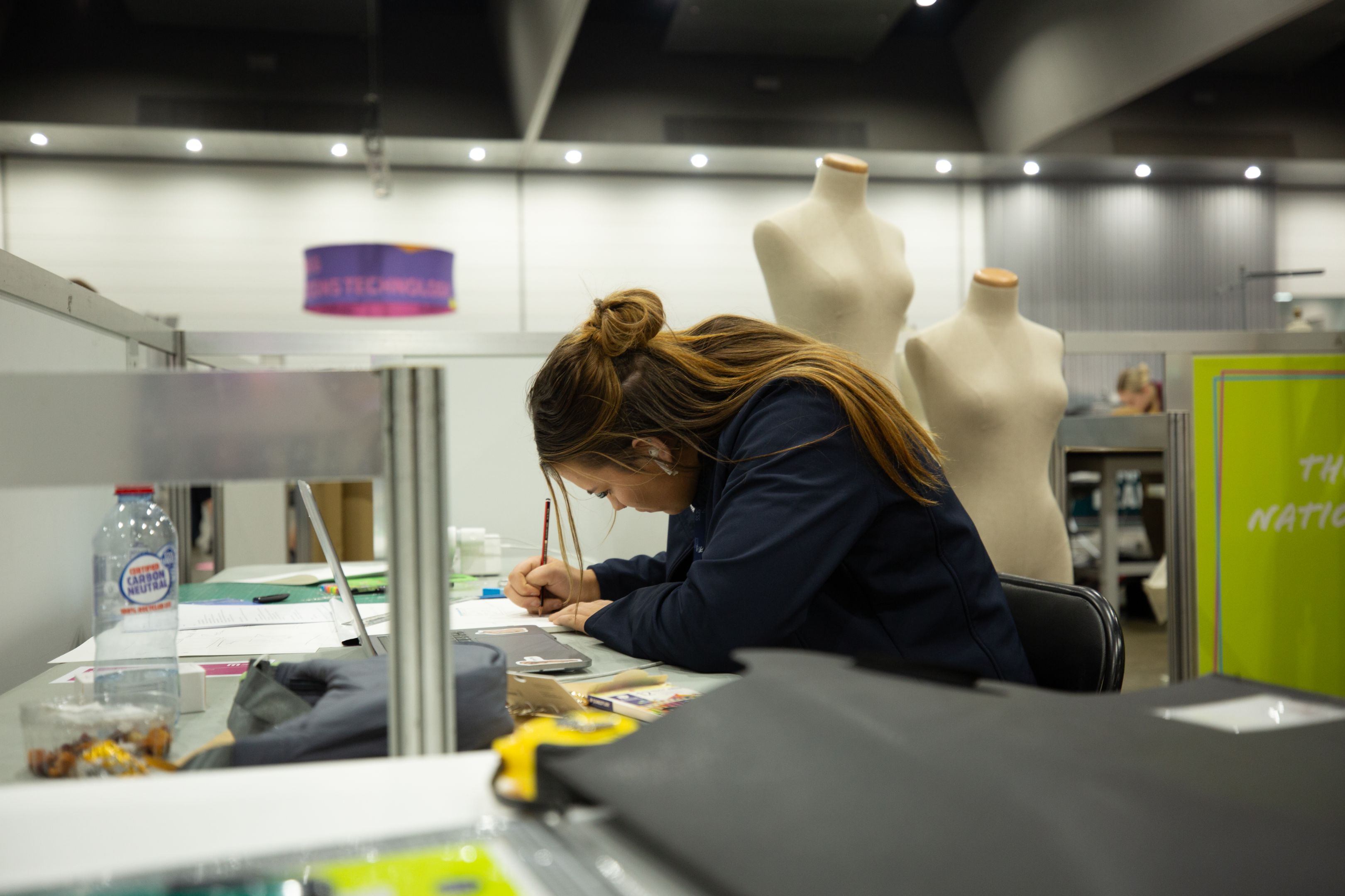 Kaitlyn sitting at a desk and drawing up designs