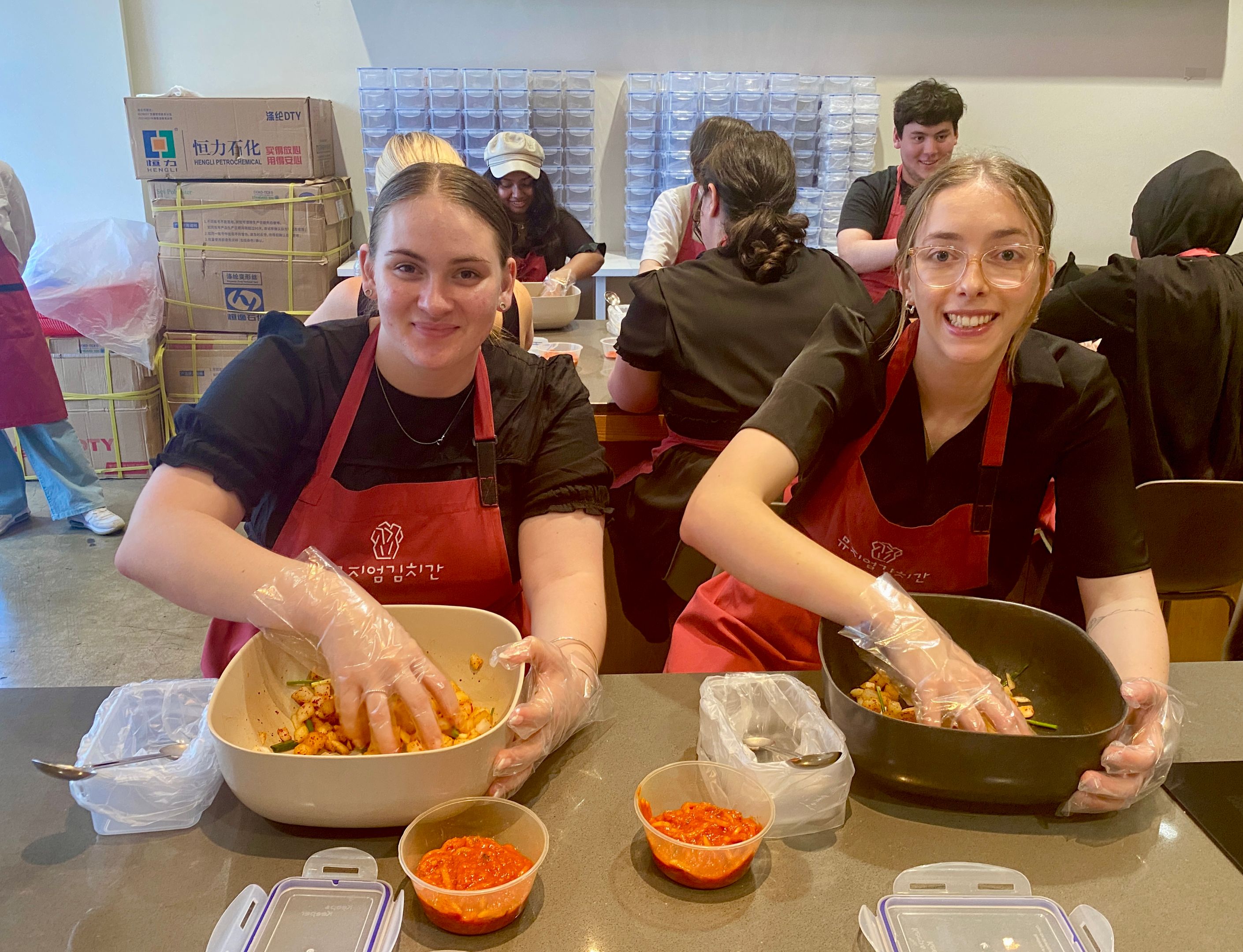 Two students mixing kimchi in a bowl during kimchi making class
