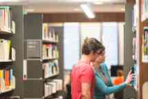 Staff helping student find a book in the library