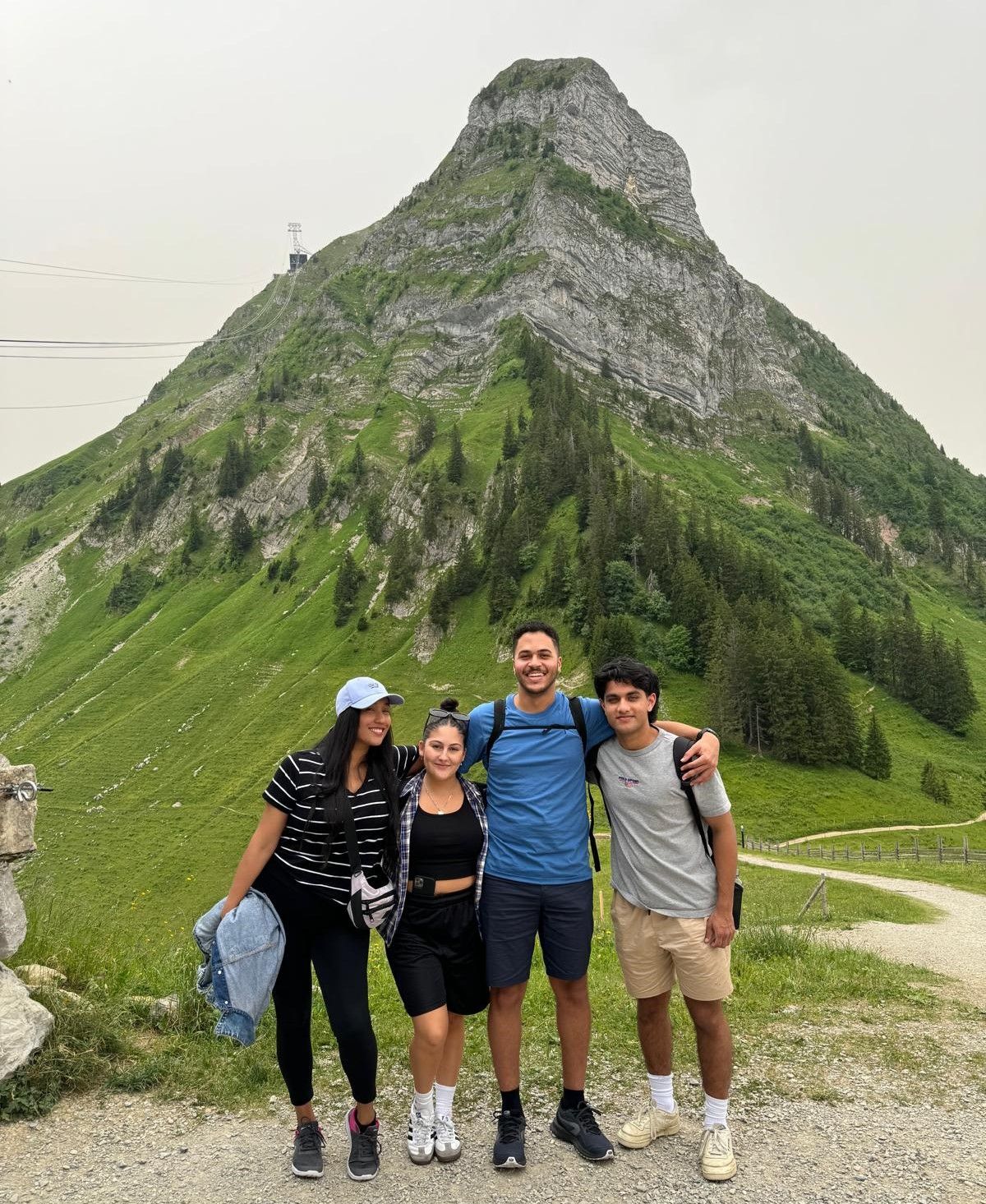 Image of 4 students standing in front of mountain in Switzerland as part of exchange program at School of Management Fribourg.