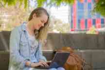 Female student sitting outside using her laptop