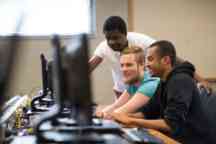 Young men smile looking at computer screen