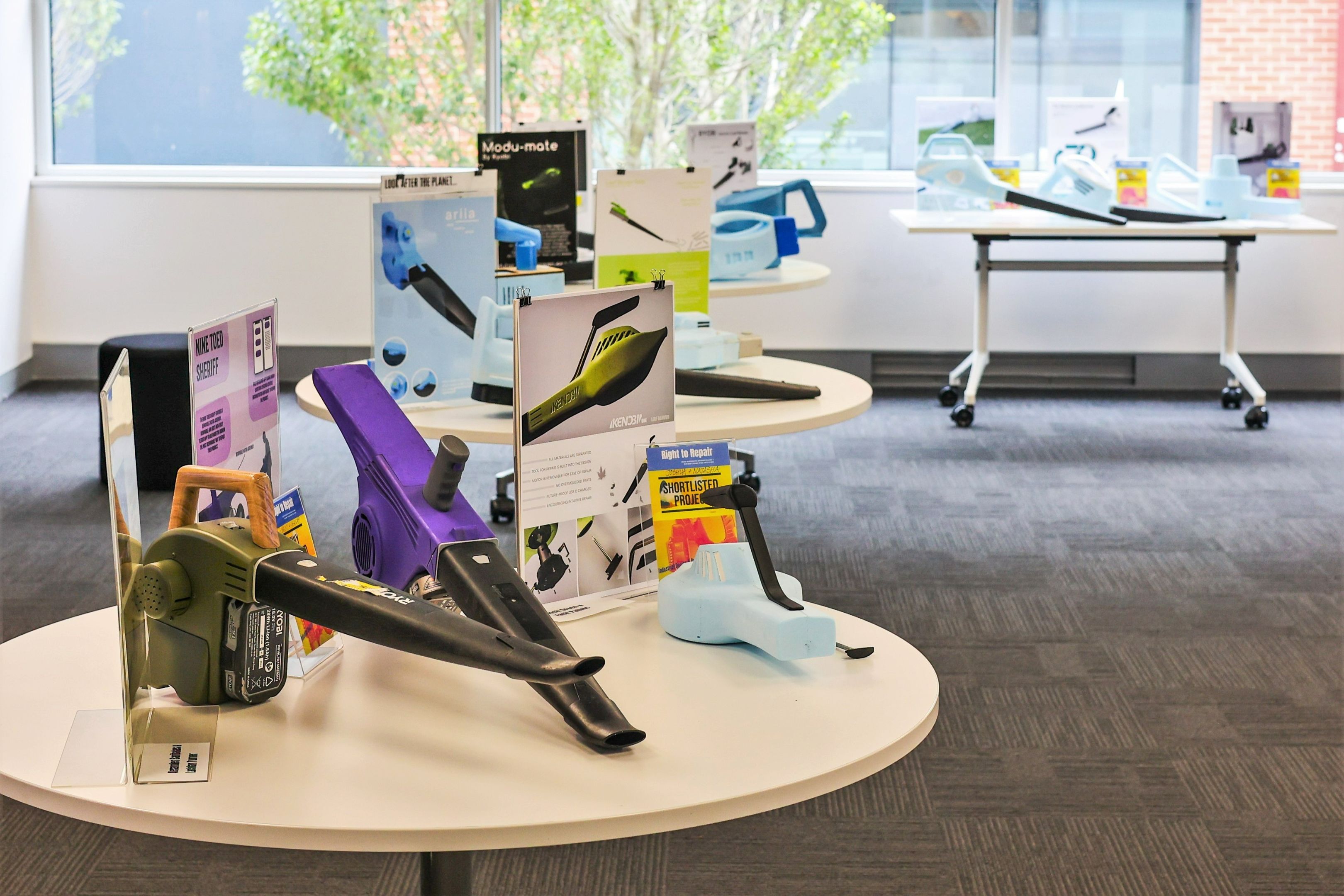 Right to repair showcase A range of leaf blower prototypes, some made from coloured plastics and others from blue sculpting foam, are displayed on tables next to informative signs