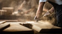 A carpenter sanding a block of wood