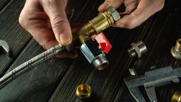 Close-up shot of a plumber's hand on a desk working with tools