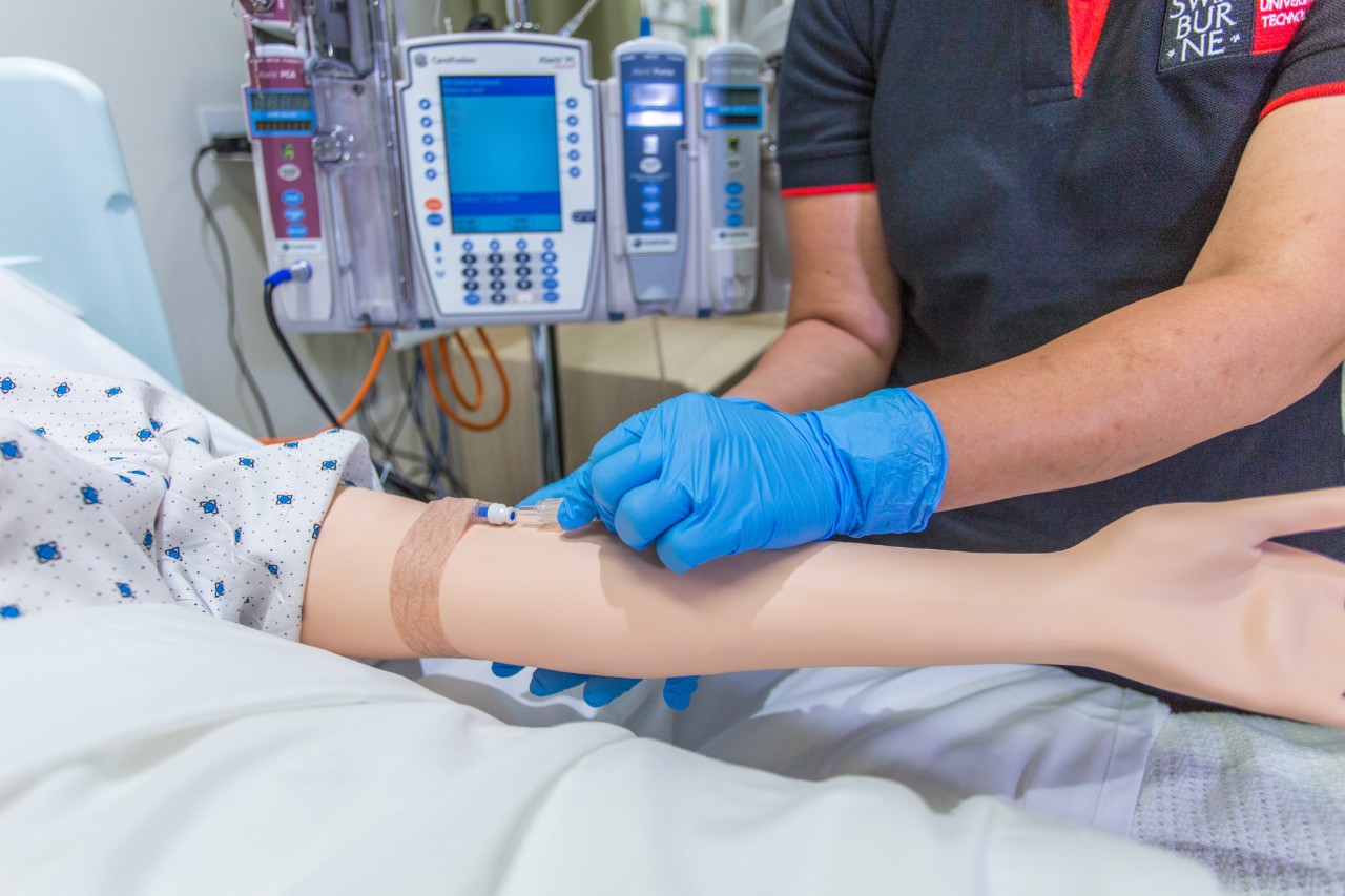 Swinburne student administers needle to dummy patient as part of their nursing training